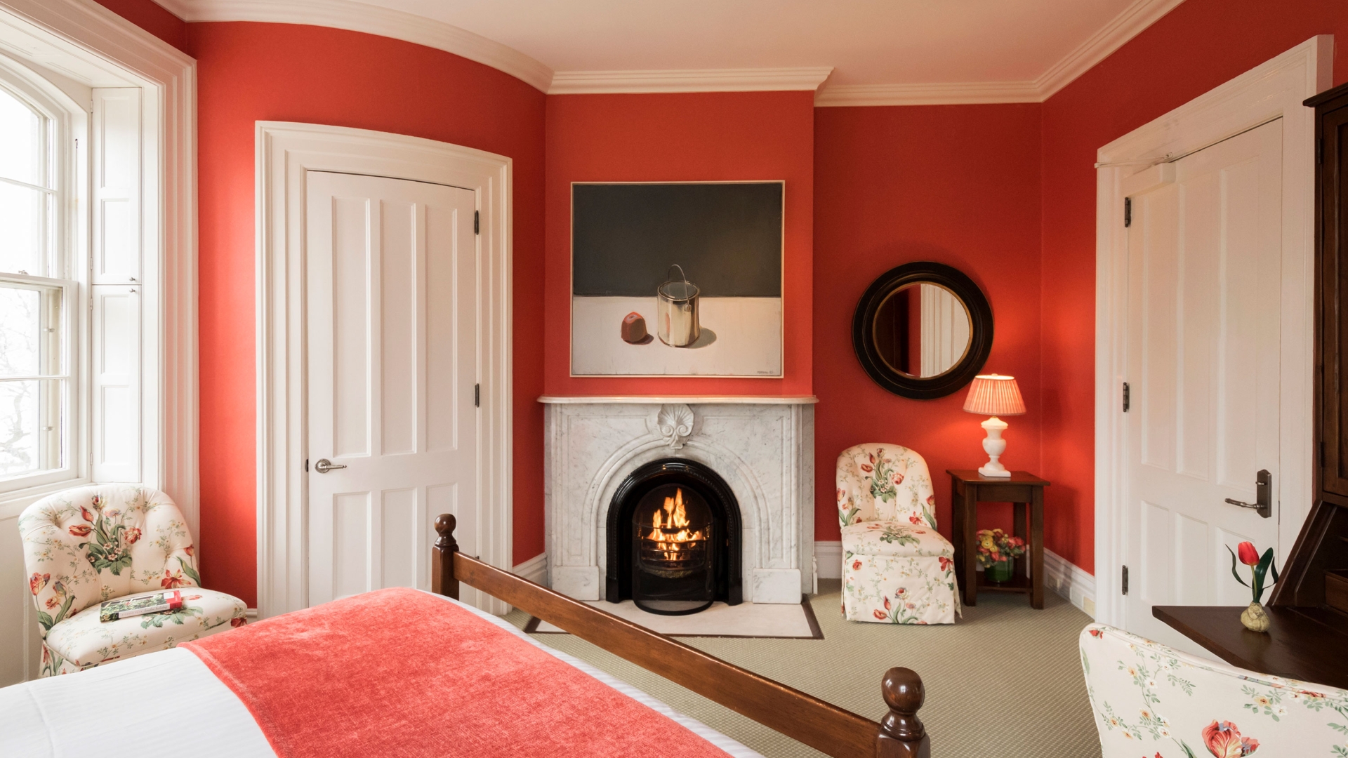 Red wall, white fireplace, and floral seating found in the Deluxe ADA room.