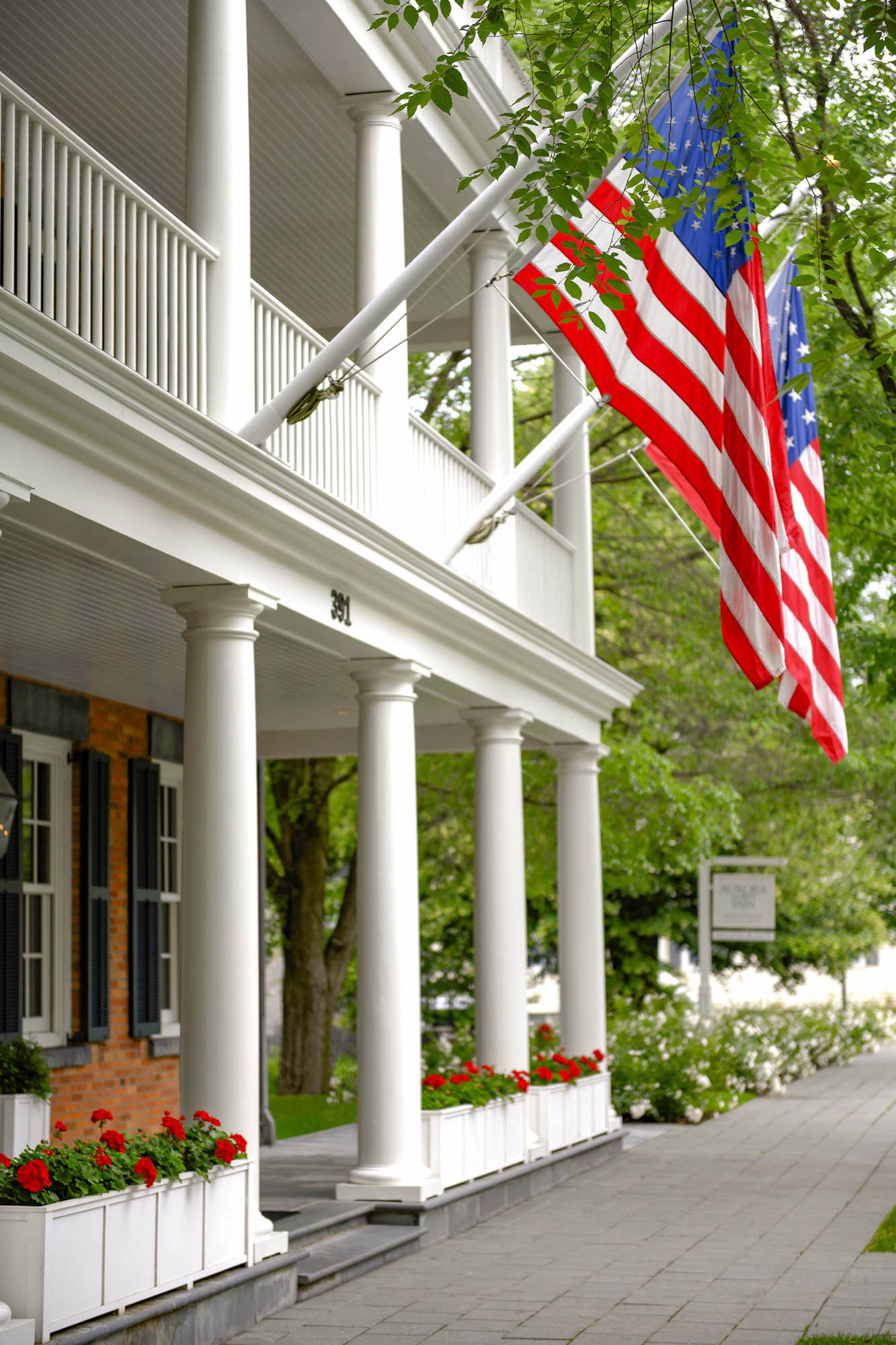 American flags hanging from front porch of Aurora Inn.