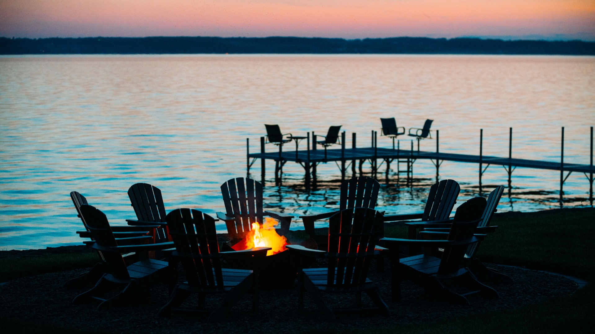 Chairs around a fire pit in front of the lake.