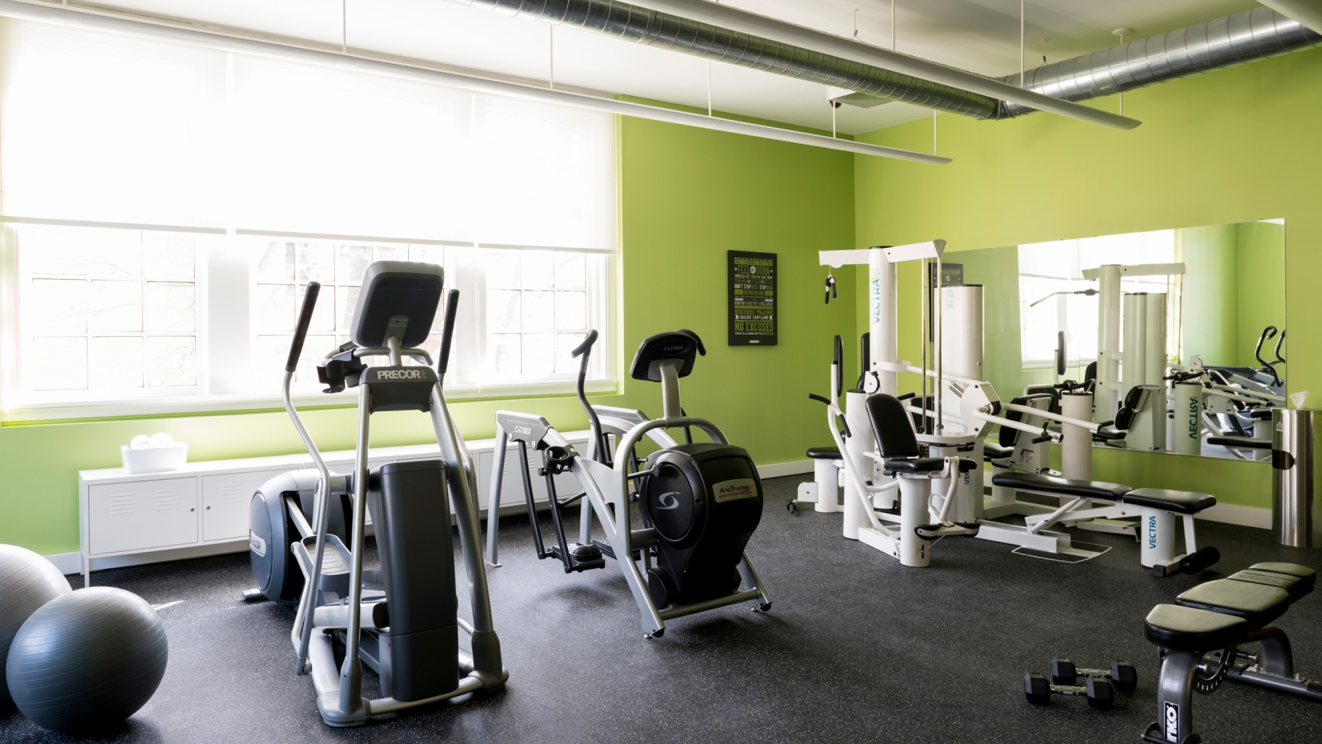 Green-walled gym room with various exercise equpitment.