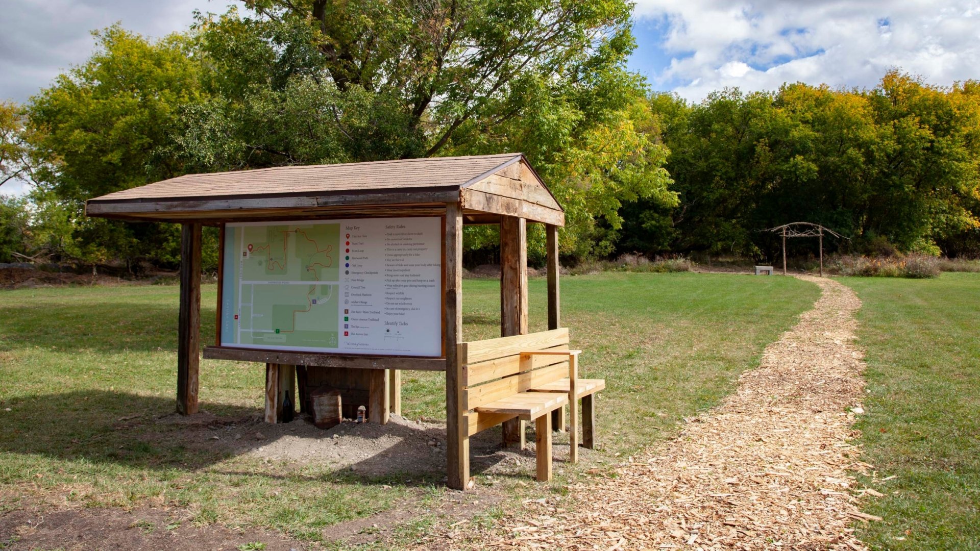 A wooden shelter with a bench and map of nature trails.
