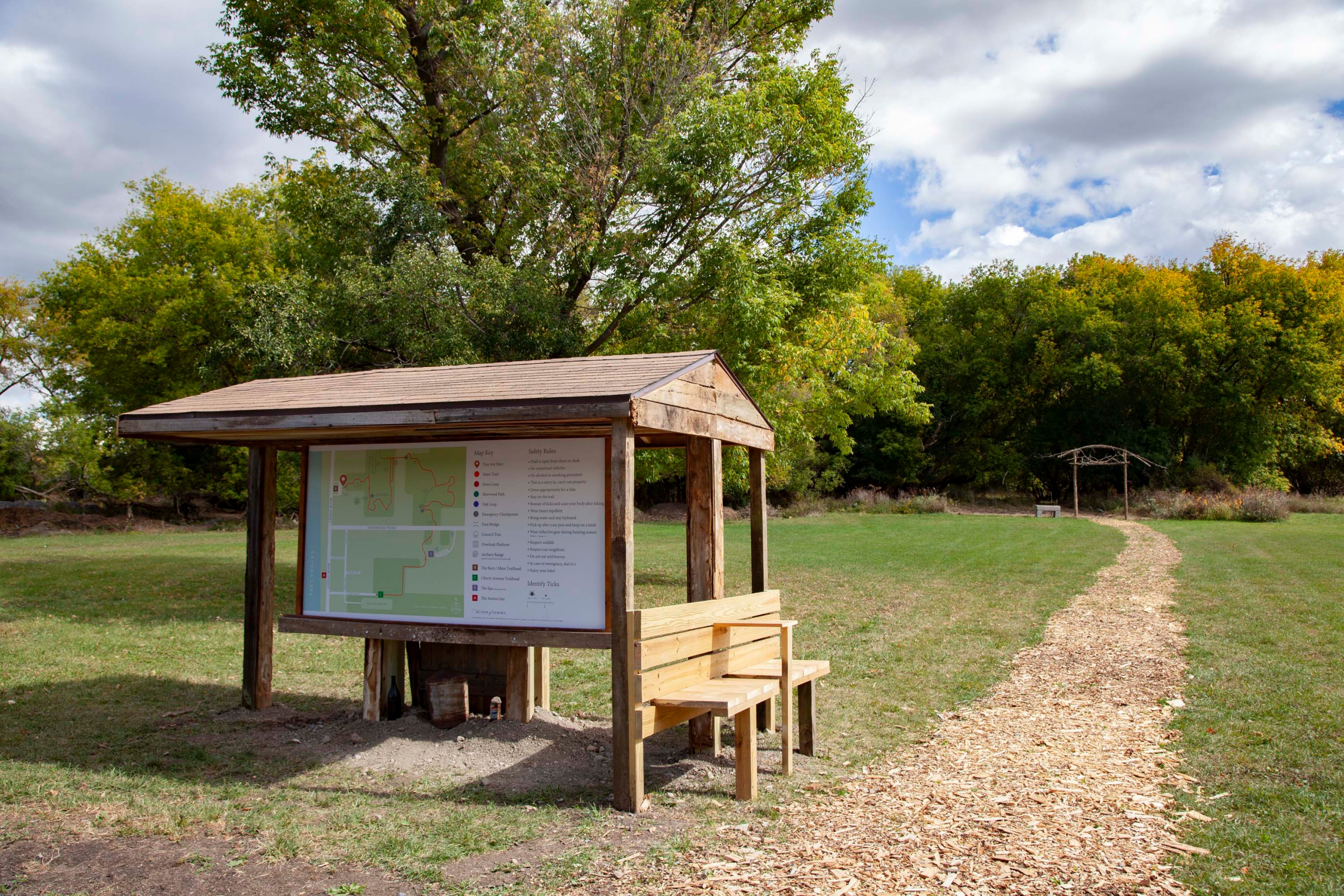 A wooden shelter with a bench and map of nature trails.