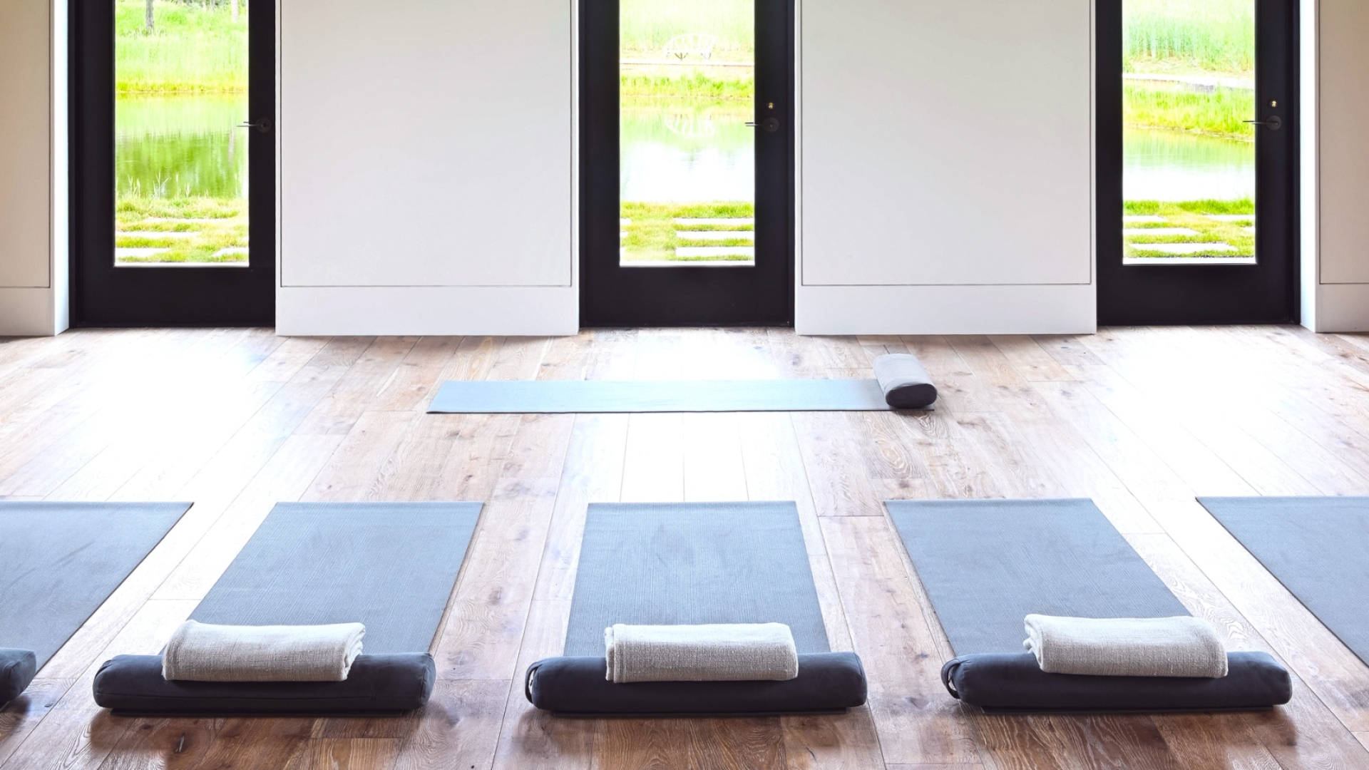 Calming yoga room with wooden floors and large windows.