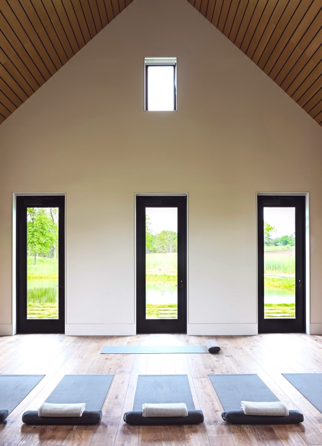 Calming yoga room with wooden floors and large windows.