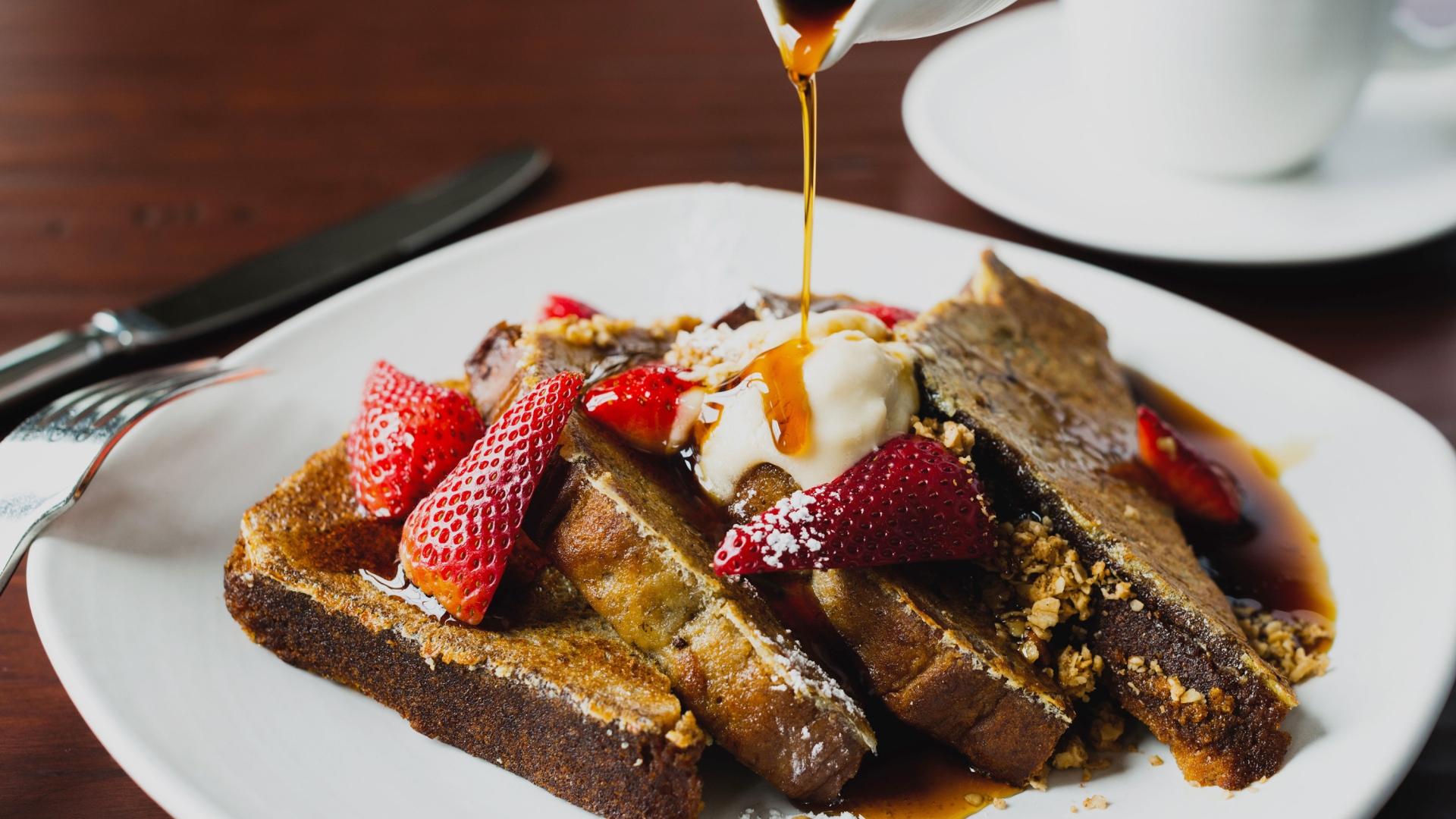 A plate of French toast topped with fresh strawberries and syrup.