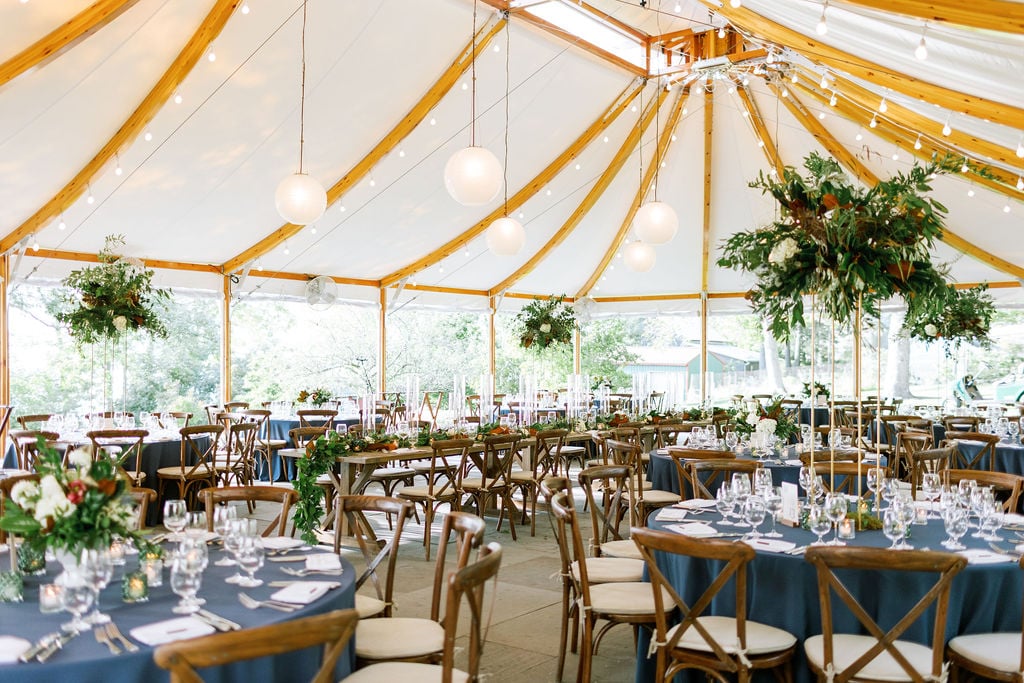A decorated wedding tent with elegant dining and floral arrangements.