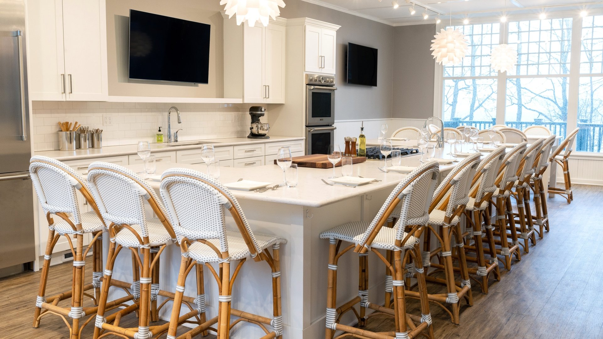 A kitchen with white cabinets and matching white counter tops and chairs.