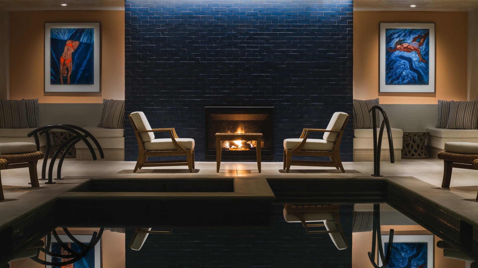 Pair of chairs in front of fireplace and pool in The Spa.