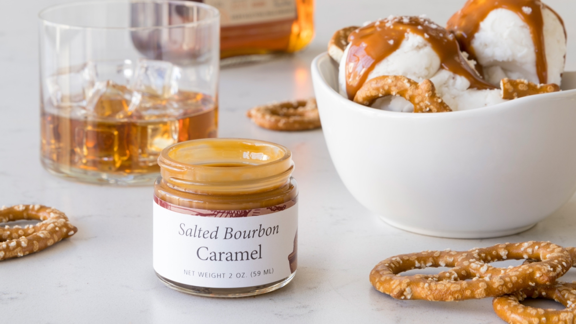 A bowl of pretzels and a bottle of whiskey paired with a Salted Bourbon Caramel Sundae.