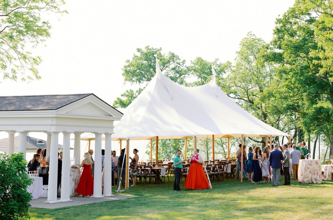 Guests mingling under wedding tent at Inns of Aurora.