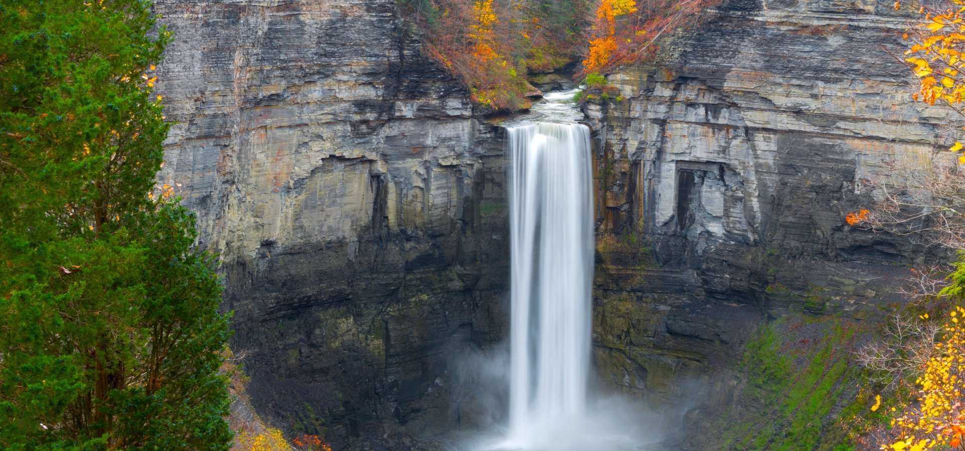 Taughannock waterfalls with vibrant leaves all around.